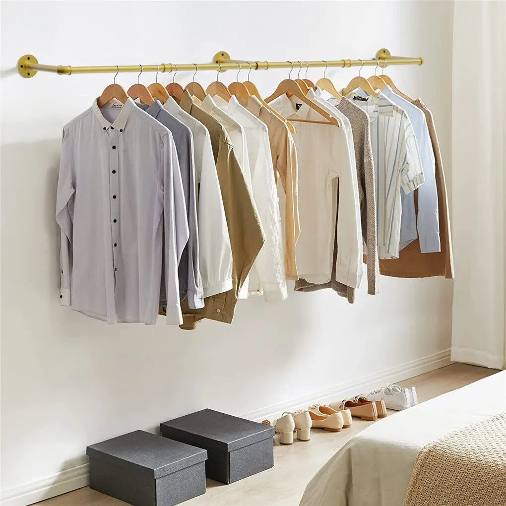 Clothing on hangers against a white wall with boxes and shoes on the floor.