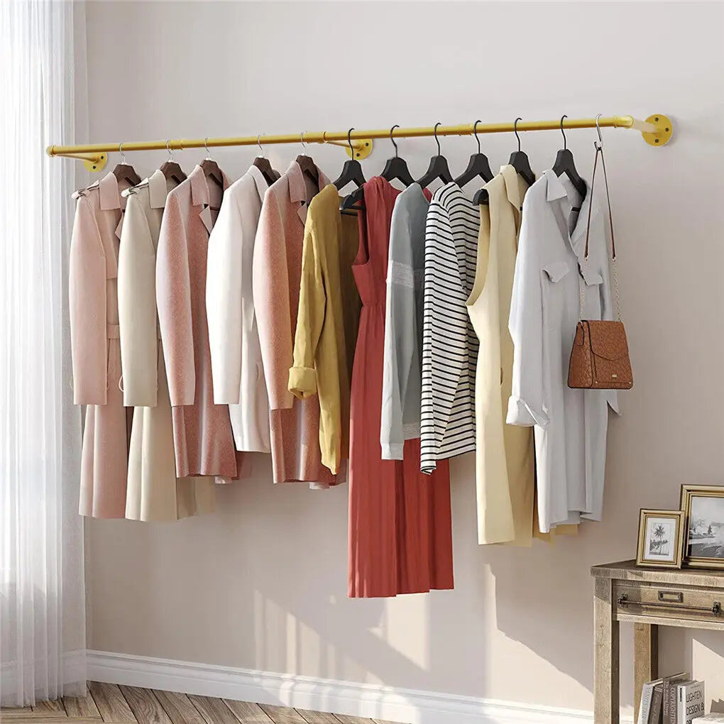 Clothing rack with various garments hanging on a white wall.
