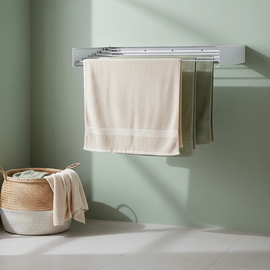 Foldable Towel rack/airer with beige and green towels against a light green wall.