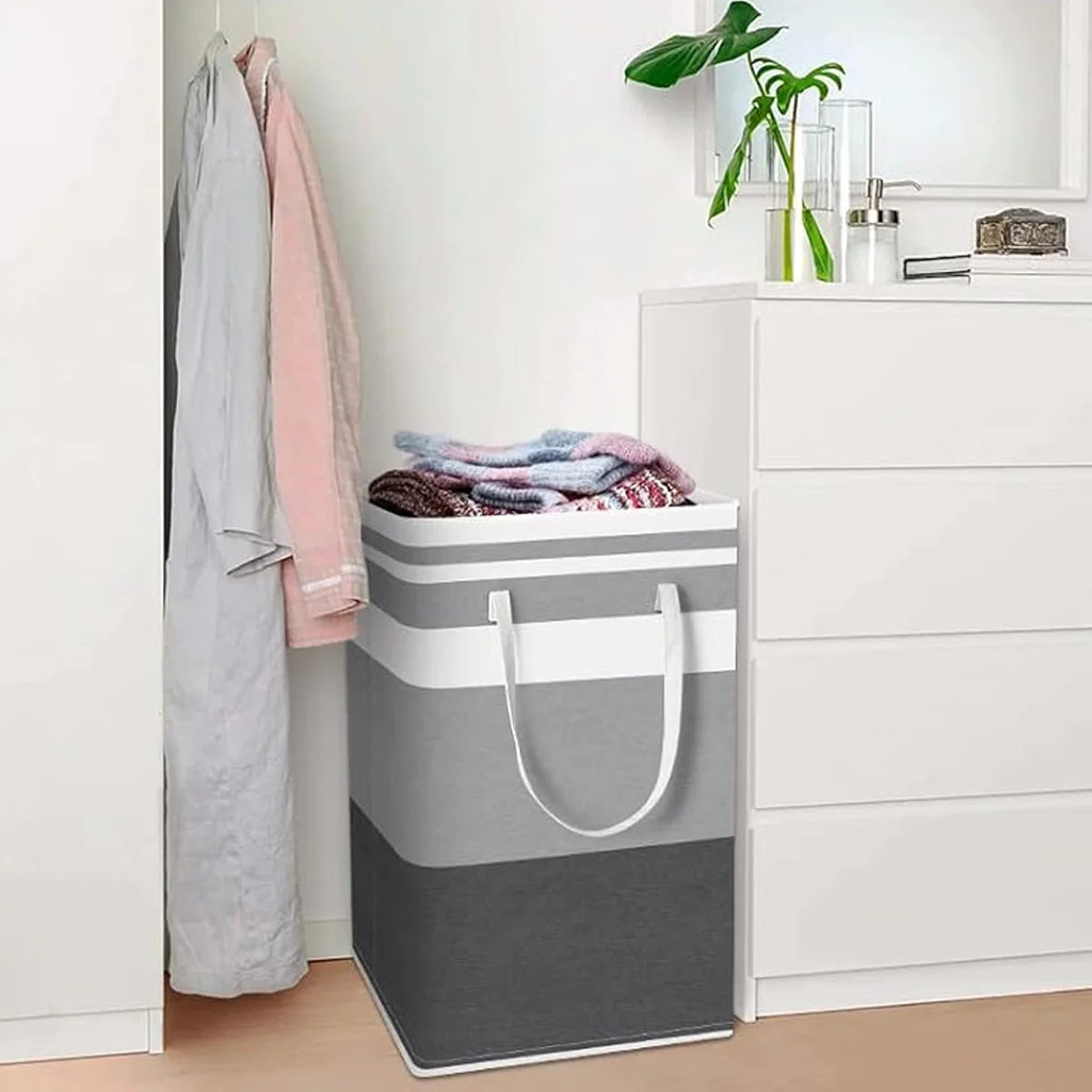 Gray and white laundry basket with clothes inside, next to a dresser.