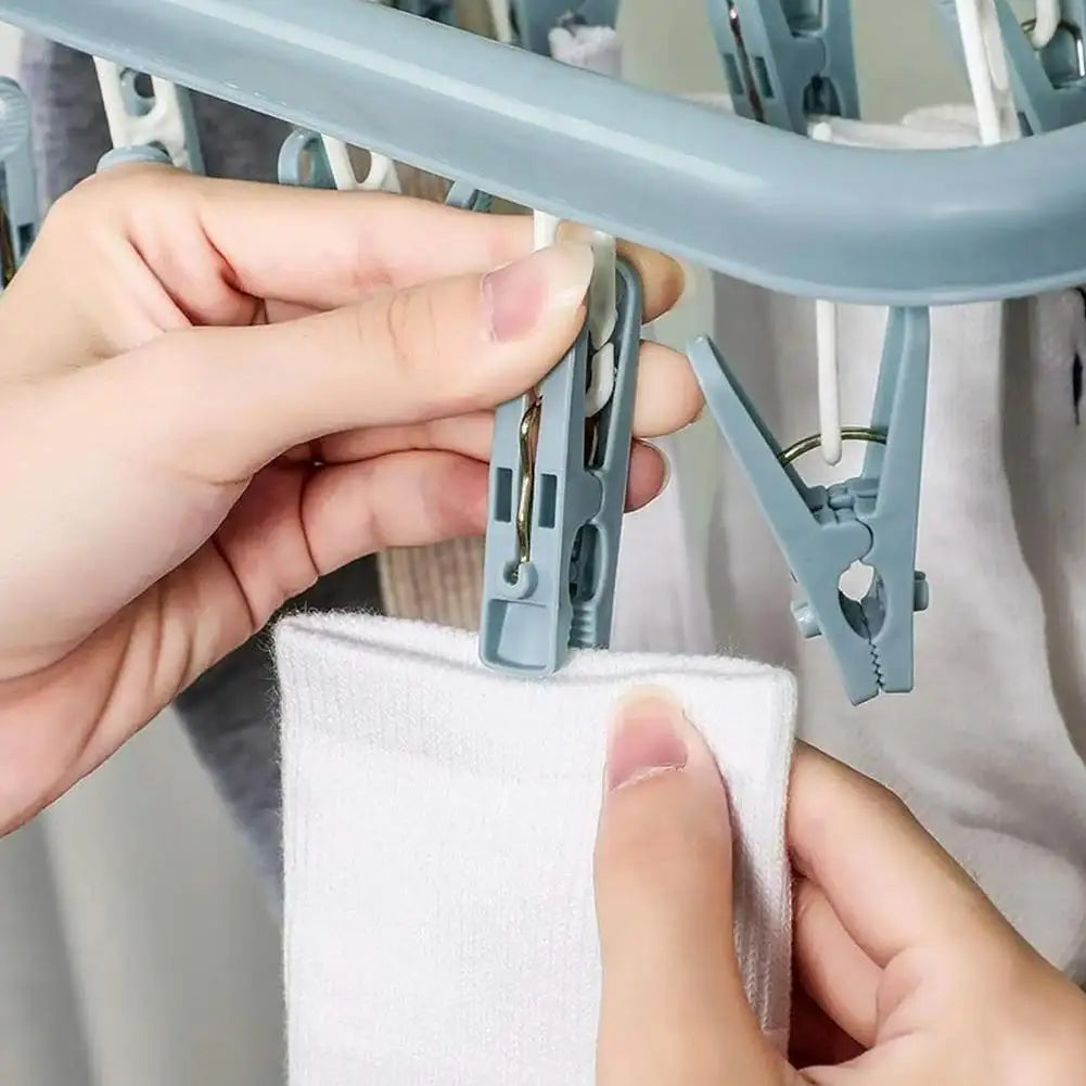 Person using a clothespin to dry a white sock on a rack.