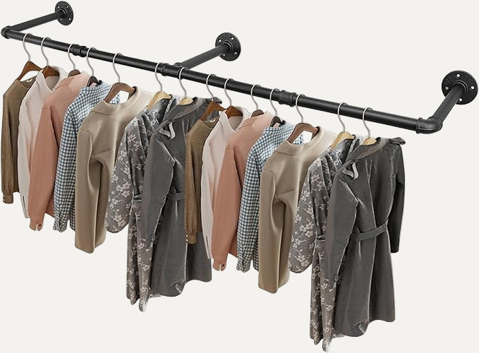Wall mounted Clothing rack/pipe with various jackets and shirts hanging on it against a white background