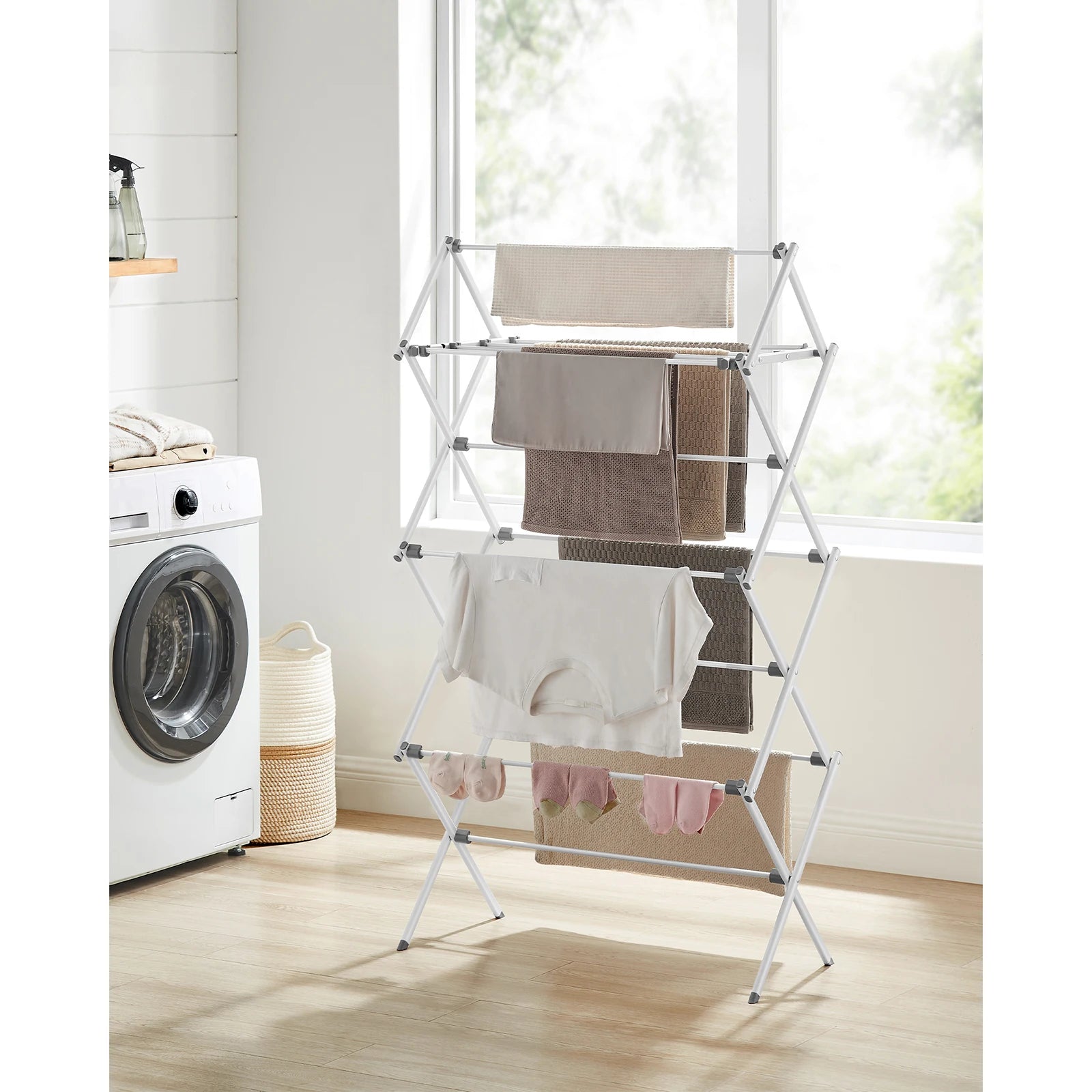 White metal drying rack/airer in a laundry room with a washing machine and basket.