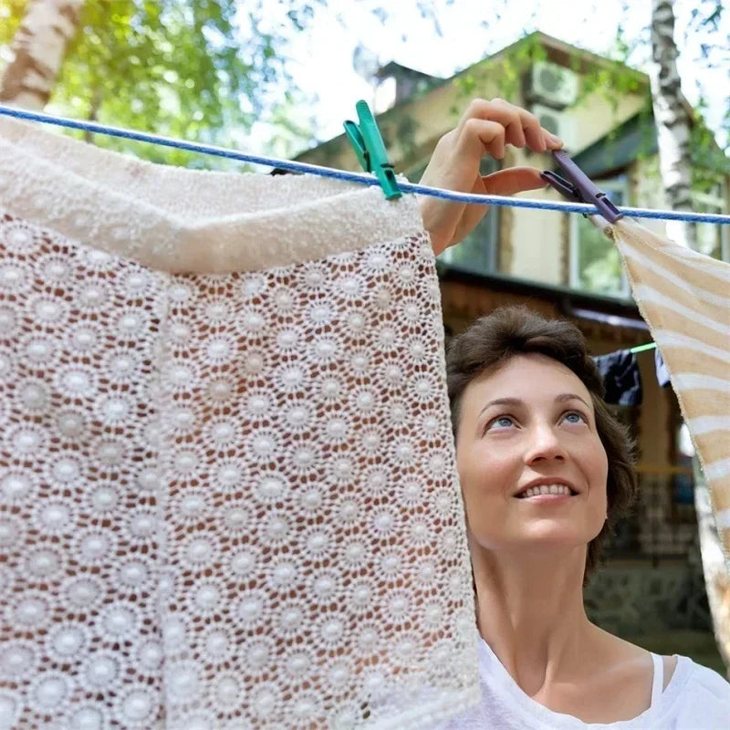 woman putting up clothes on a clothes line holding a clothespin in her hand